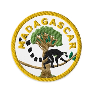 May include: An embroidered patch featuring the word "MADAGASCAR" in a circle around a green tree with a black lemur sitting on a branch.
