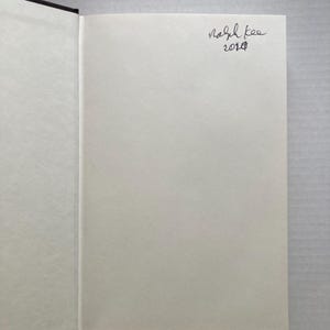 May include: A blank white page of a book with black binding. The page has a handwritten signature that says "Ralph Lee 2018".