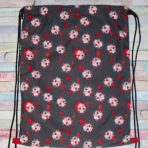 Puede incluir: Una bolsa de cordón negro con un patrón de calavera roja y blanca. La bolsa tiene un cordón negro y detalles rojos.
