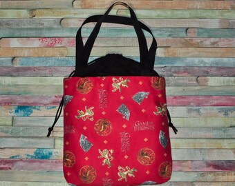 May include: Red drawstring bag with black handles. The bag is printed with a repeating pattern of the Game of Thrones logo, a direwolf, and the words "Game of Thrones".