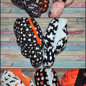 K&ouml;nnte beinhalten: Acht Pl&uuml;schtiere zum Thema Halloween mit verschiedenen Mustern. Die Spielzeuge sind schwarz, wei&szlig; und orange mit verschiedenen Designs, darunter Flederm&auml;use, K&uuml;rbisse, Geister, Mais und Skelette.