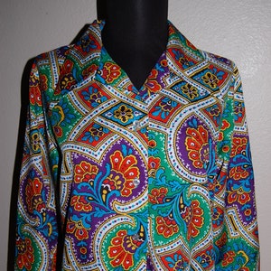 May include: A long-sleeved shirt with a paisley pattern in shades of green, purple, red, yellow, and blue. The shirt has a button-up front and a collar.