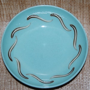 May include: A light blue ceramic bowl with a white and brown swirl design around the rim.