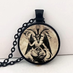 Può includere: Collana a catena nera con un ciondolo rotondo che presenta un'illustrazione vintage di una figura con testa di capra con ali e corna.