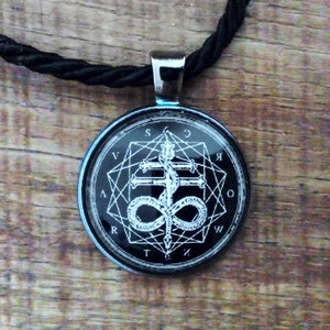 May include: A black and white pendant necklace with a silver chain. The pendant features a pentagram with a snake wrapped around it and the letters "S.C.R.V.T.W.K.O.M." around the outside.