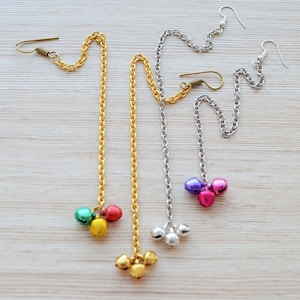 May include: Three gold and silver chains with dangling bells. The bells are in different colours, including green, red, purple, and pink.