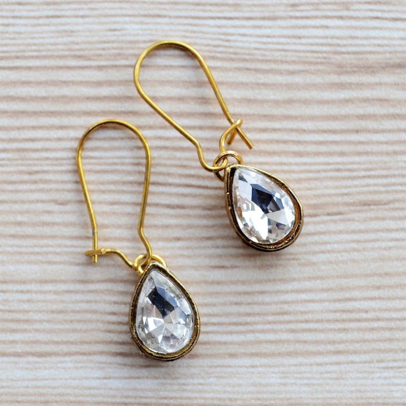 May include: A pair of gold teardrop earrings with clear crystal stones.