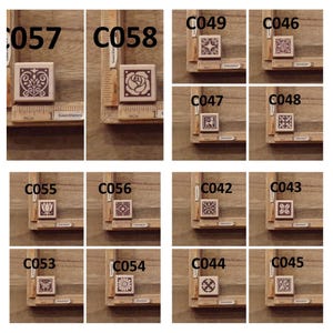 May include: A set of 12 wood mounted rubber stamps with various geometric and floral designs. The stamps are arranged in a grid pattern on a wooden surface. The stamps are labeled with numbers C042 through C058.
