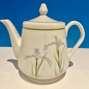 Può includere: Teiera in porcellana bianca con un bordo verde e un motivo floreale di iris viola.