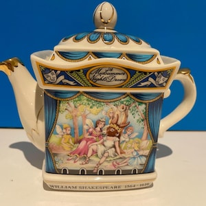 Può includere: Una teiera in porcellana bianca con un designo blu e oro. La teiera presenta una scena tratta dall'opera di Shakespeare, Sogno di una notte di mezza estate. Il testo "A Midsummer Night's Dream" e "William Shakespeare 1564-1616" è stampato sulla teiera.