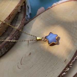 May include: A gold chain necklace with a star-shaped pendant. The pendant is made of iridescent white stone.