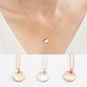 May include: Three delicate necklaces with hammered disc pendants in gold, silver, and rose gold. The necklaces are on a white background.