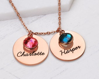 May include: Rose gold necklace with two round pendants. The pendants feature a pink and blue gemstone and the names "Charlotte" and "Harper" engraved on them.
