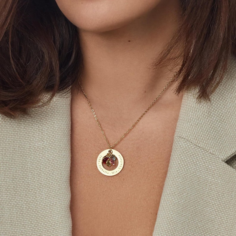 May include: Gold necklace with a round pendant engraved with the names "John, Isabella, Mrs. Christina" and adorned with colorful gemstones.