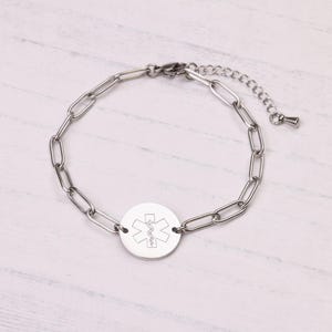 May include: A silver-colored medical alert bracelet with a chain link design. The bracelet features a circular pendant with the Star of Life symbol engraved on it. The bracelet is adjustable and has a lobster clasp closure.
