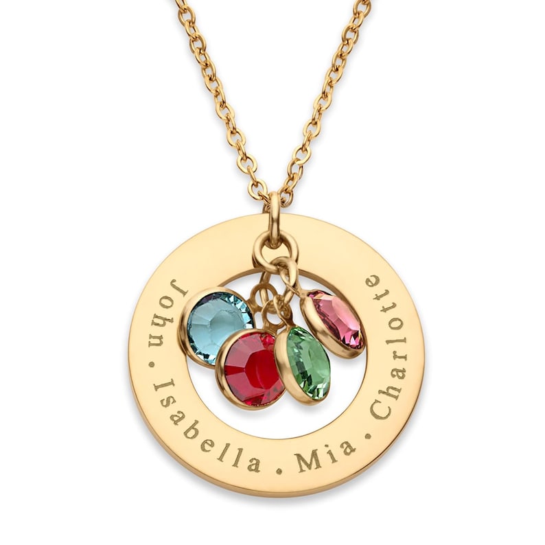 May include: Gold necklace with a round pendant engraved with the names "Mia", "Isabella", "John", and "Charlotte". The pendant has a charm with four colorful crystals.