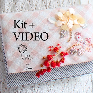 Könnte beinhalten: Eine rosa-weiße Gingham-Stofftasche mit einem perlenbesetzten Blumenmuster und dem Text "Kit + VIDEO".