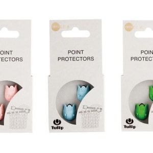May include: Three packs of Tulip brand point protectors. Each pack contains two plastic point protectors shaped like tulips. The packs are labelled "Point Protectors" and feature the Tulip logo. The point protectors are available in pink, blue and green.