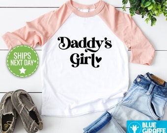 May include: A white and pink baseball tee shirt with the text "Daddy's Girl" in black with a heart.