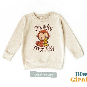 May include: A beige sweatshirt with a cartoon monkey holding a banana and the text "chunky monkey" printed on the front.
