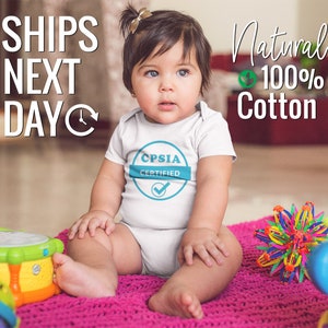 May include: White baby bodysuit with CPSIA Certified logo.  Made of 100% natural cotton. Ships next day.  The bodysuit features a teal circular logo with white text. The text on the image says 'SHIPS NEXT DAY' and 'Natural 100% Cotton'.