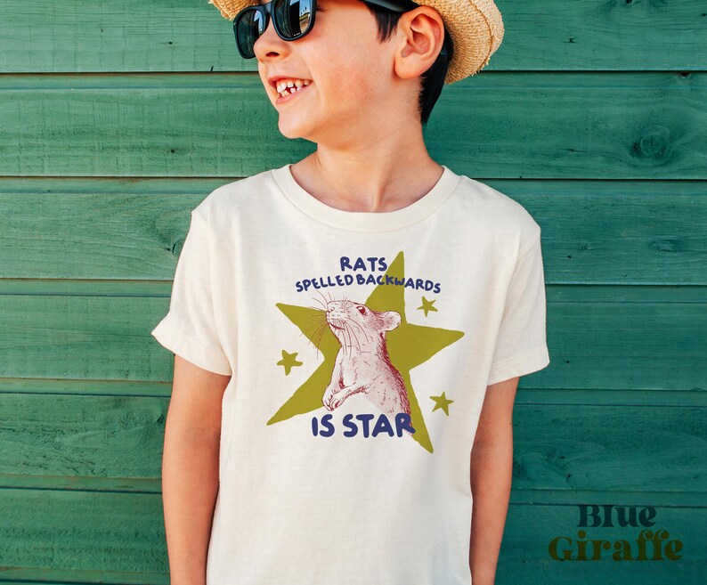 May include: Off-white t-shirt with a graphic of a rat inside a green star, with the text "RATS SPELLED BACKWARDS IS STAR". The shirt also has the text "Blue Giraffe" in the bottom right corner.