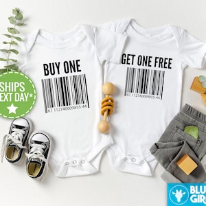 Puede incluir: Dos bodies blancos para bebé con texto negro y códigos de barras. El body de la izquierda dice "Compra uno" y el body de la derecha dice "Lleva uno gratis".