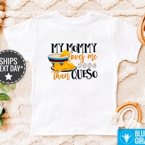 May include: White t-shirt with a graphic of a bowl of queso and the text "My Mommy loves me more than Queso".
