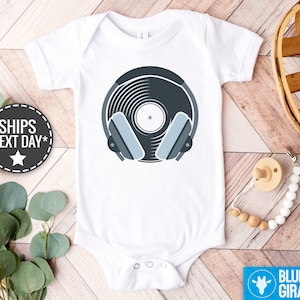 May include: White baby onesie with a blue and gray vinyl record with headphones on it.