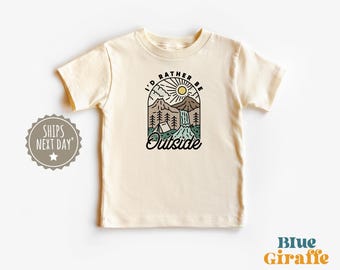 May include: A cream colored t-shirt with a graphic of a mountain scene with a waterfall and a tent. The text "I'd rather be outside" is printed on the shirt.
