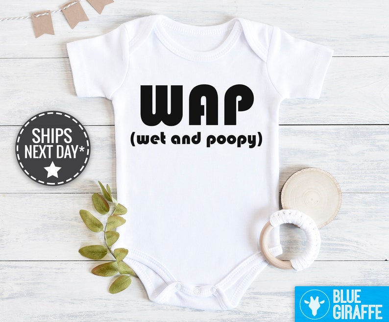 以下が含まれることがあります： 白いベビーロンパースに、黒い文字で「WAP（ウェットアンドプーピー）」と書かれています。