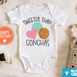 May include: White baby onesie with the text "Sweeter than Conchas" and a graphic of three colorful conchas.