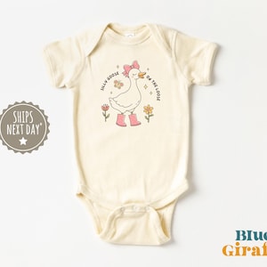 Peut inclure: Body de bébé crème avec un dessin d'oie portant un nœud rose et des bottes, entourée de fleurs. Le texte dit "Silly Goose on the Loose". Le body a des manches courtes et des boutons-pression.