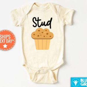 May include: A white baby onesie with the text "Stud" and a cartoon muffin with chocolate chips on top.