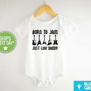 May include: White baby onesie with black text that reads "Born to Jam Just Like Daddy" and five black electric guitar silhouettes.