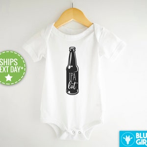 Puede incluir: Un body blanco para bebé con una ilustración negra de una botella de cerveza y el texto "IPA lot".