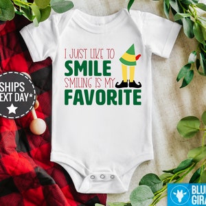 May include: White baby onesie with green and red text that reads "I just like to smile smiling is my favourite". A cartoon elf with green hat and red shoes is above the text.