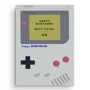 Könnte beinhalten: Graue Geburtstagskarte im Retro-Handheld-Konsolen-Design. Der Bildschirm zeigt "HAPPY BIRTHDAY, NEXT LEVEL, 40." Die Karte hat ein Steuerkreuz, rosa Knöpfe und die Worte "Happy BIRTHDAY" unten in Blau.