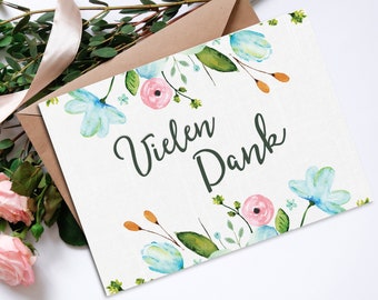 May include: A white card with a watercolour floral border and the text "Vielen Dank" in green lettering.