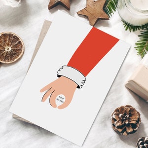 Könnte beinhalten: Eine weiße Karte mit einer rot-weißen Weihnachtsmann-Hand, die einen weißen Kreis mit dem Text "Merry Christmas" hält.