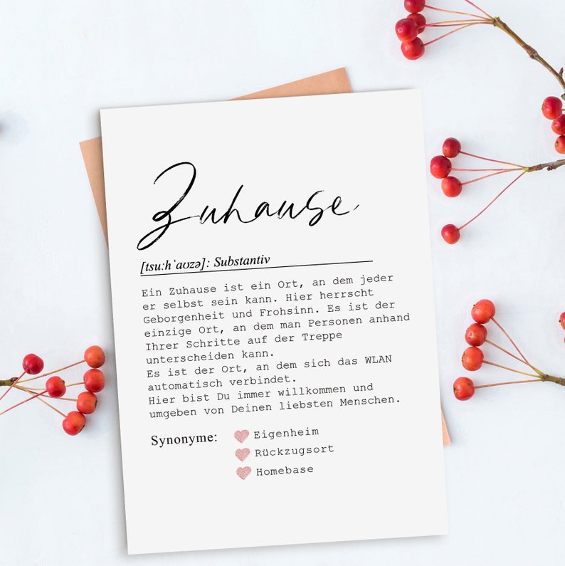May include: A white card with black text defining the word "Zuhause" as a German noun. The text explains that a home is a place where one can be themselves, a place of safety and joy. The card also lists synonyms for "Zuhause" in German, including "Eigenheim", "R&uuml;ckzugsort", and "Homebase".