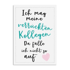 Op de afbeelding: Een witte kaart met zwarte en turquoise tekst die "Ich mag meine verr&uuml;ckten Kollegen Da falle ich nicht so auf" zegt met een roze hart in de rechterbenedenhoek.