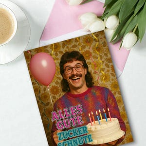 May include: A birthday greeting card featuring a man with a mustache holding a cake with lit candles. The card has the text "ALLES GUTE ZUCKER SCHNUTE" in pink and blue. A pink balloon is visible.