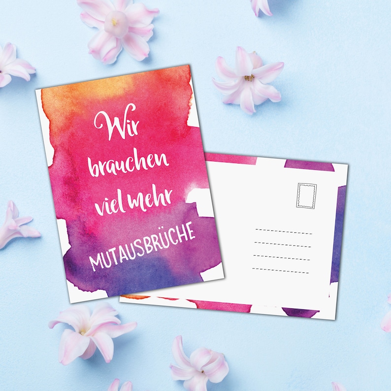 Pode incluir: Um cart&atilde;o postal com um fundo de aquarela em tons de rosa, laranja e roxo. O texto na frente diz "Wir brauchen viel mehr MUTAUSBR&Uuml;CHE". O verso do cart&atilde;o postal est&aacute; em branco com espa&ccedil;o para um selo.