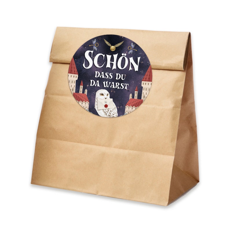 May include: A brown paper bag with a round sticker featuring a white owl with a letter in its beak. The sticker has a dark blue background with white stars and the text "SCH&Ouml;N DASS DU DA WARST".
