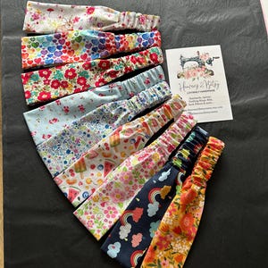 May include: A set of 10 colourful headbands with various patterns, including floral, hearts, rainbows, and ice cream. The headbands are made of soft fabric and have a stretchy elastic band for a comfortable fit. The headbands are handmade and are perfect for adding a touch of style to any outfit.