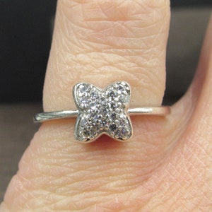 May include: A silver ring with a small, clear, crystal butterfly design.
