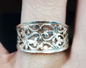May include: A silver filigree ring with a wide band and intricate heart-shaped designs.