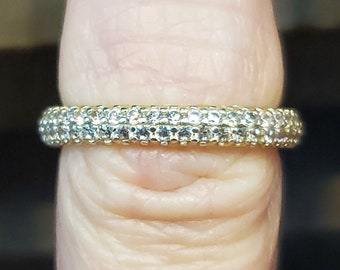May include: A gold band ring with a double row of small, clear cubic zirconia stones.