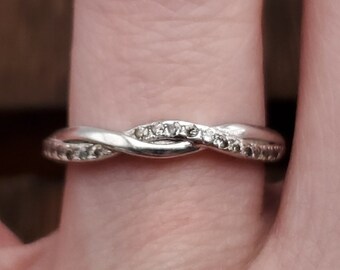 May include: A silver band ring with a twisted design and small diamonds set in the band.